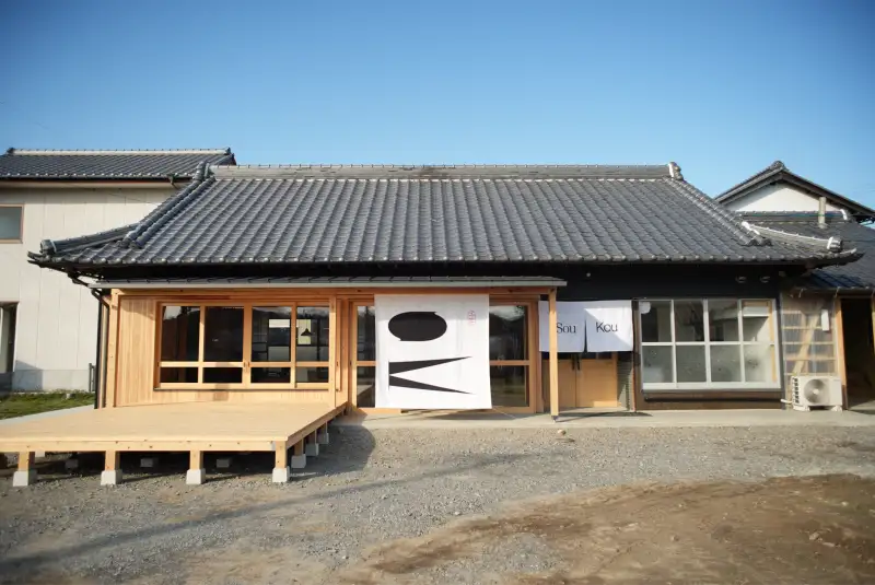 瓦屋根と木のデッキのある古民家の外観