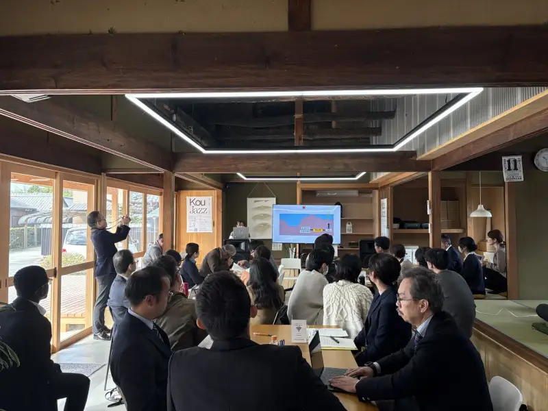 古民家の会場で、前に立つ発表者のスライドを着席して聞く参加者たち