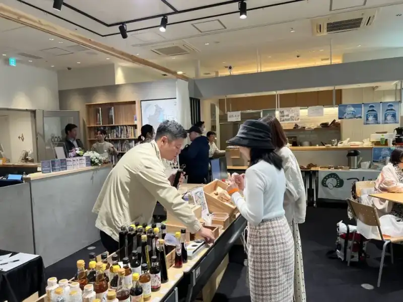 醤油や調味料の瓶が並ぶ販売スペースで、出店者と来場者が話している